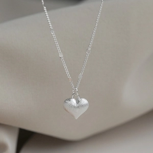 Elegant heart pendant necklace with matte silver finish on a minimalist designer chain