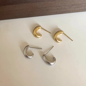 Detail of C-shaped matte S925 silver stud earrings in gold and silver finishes