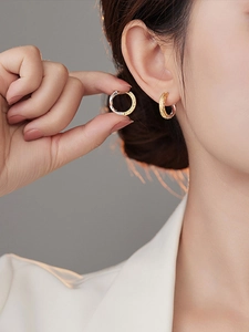 Close-up of textured two-tone gold and silver earrings on model featuring retro patterns