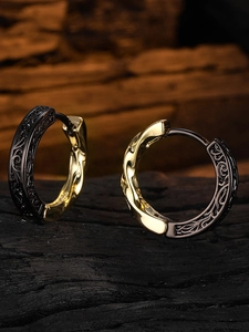 Detailed view of bicolor metal hoop earrings featuring gold texture and black vintage patterns