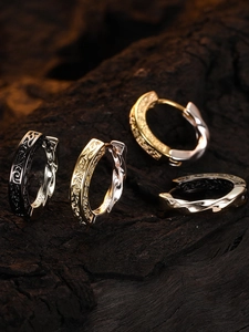 Detailed view of vintage S925 silver hoop earrings with intricate relief texture on dark wood