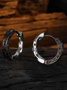 Macro shot of gothic vintage earrings with textured engraving on a dark stone base