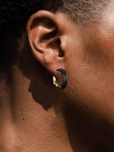 Close-up of retro contrast color ear hoops with black textured patterns and golden polish