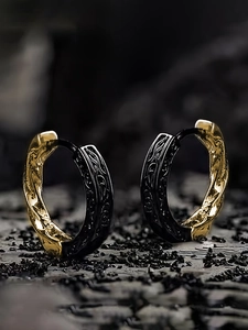 Macro detail of two-tone gold and black twisted earrings with vintage textured engraving