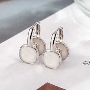 Macro view of silver hoop earrings featuring white square enamel inlay detail