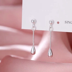 Macro shot of silver teardrop long tassel earrings with sleek chains on silk background