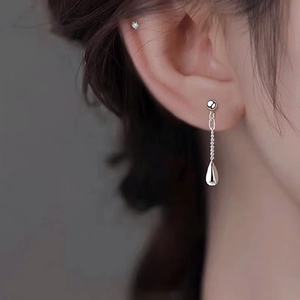 Close-up of elegant long silver tassel earrings with a polished teardrop pendant