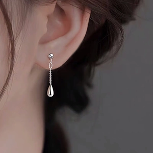 Close-up of elegant silver teardrop tassel earring on model with high gloss finish
