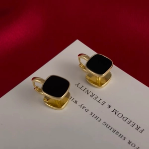 Elegant gold square hoop earrings with black enamel inlay on silk background