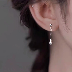 Minimalist silver teardrop tassel earrings shown on a model with sleek chain and polished finish