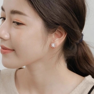 Elegant silver four-leaf clover hollow flower stud earrings worn by a female model
