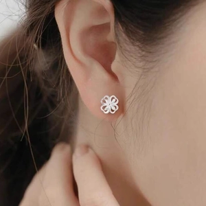Chic silver hollow four-leaf flower stud earring worn by a model for a trendy minimal look