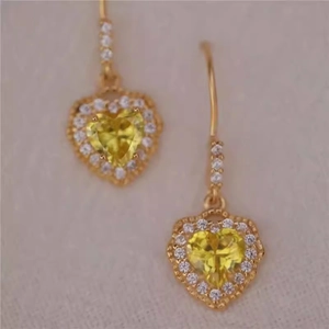 Detail of vintage heart earrings with yellow gemstones and gold-plated micro-pave crystals