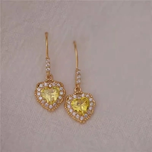Macro detail of French vintage heart earrings with yellow crystal and gold plating