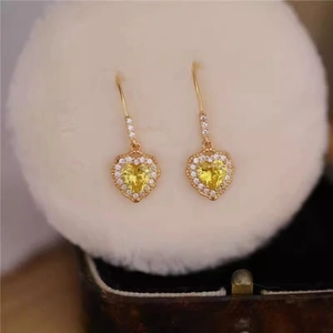 Detail of vintage heart-shaped gold drop earrings with yellow zircon and pavé crystals