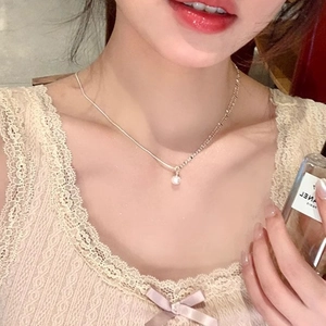 Minimalist silver necklace with zircon pendant on a woman wearing pink lace clothing