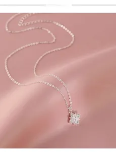 Close-up of silver clover pendant with zircon crystals on pink satin background
