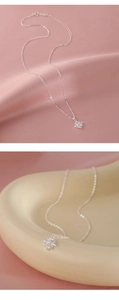 Detailed close-up of a silver cross pendant with sparkling zircons on soft pink silk