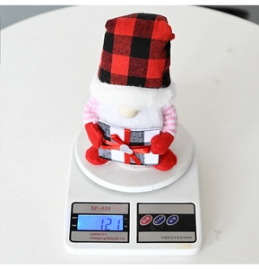 Mesure du poids d'un lutin de Noël avec chapeau à carreaux rouges et boîte cadeau