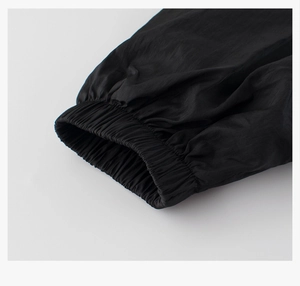 Détail du poignet élastique coupe-vent sur une veste noire pour enfant en tissu mat