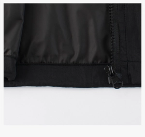 Détail de l'ourlet de la veste noire pour enfants avec zip et texture coupe-vent