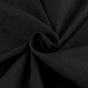 Détail du tissu noir texturé montrant le drapé et la finition mate de la veste à capuche
