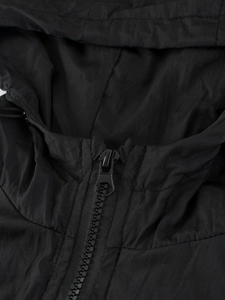 Détail d'une veste à capuche noire pour enfants avec fermeture éclair en résine