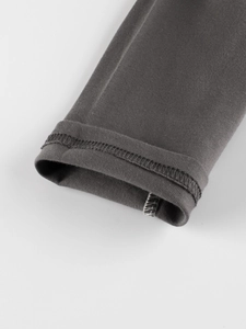 Detail of dark grey knit raglan sleeve cuff showing high-quality overlock stitching