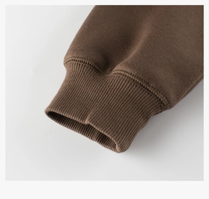 Gros plan des poignets côtelés du sweat à capuche marron avec coutures et maille épaisse
