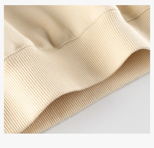Gros plan des poignets côtelés beige et de la texture en maille de coton dense du sweat-shirt