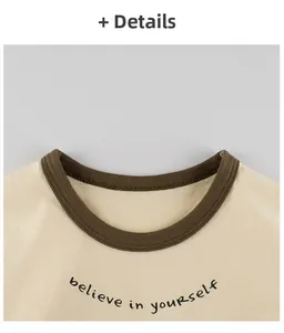 Détail de l'encolure ronde avec bordure marron et motif imprimé sur le t-shirt beige fille