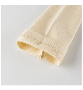 Gros plan sur la couture double aiguille des manches en coton tricoté jaune pour enfants