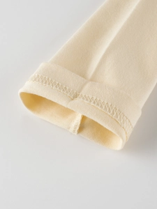 Détail des poignets en tricot côtelé sur un t-shirt crème à manches longues pour filles