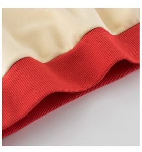Detail of red ribbed hem and beige knit fabric on children's crewneck sweatshirt