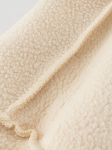Detailed macro view of soft beige polar fleece fabric with premium stitching craftsmanship