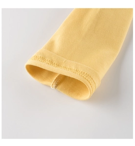 Close-up of yellow knit cotton long sleeve cuff showing precise double-needle stitching