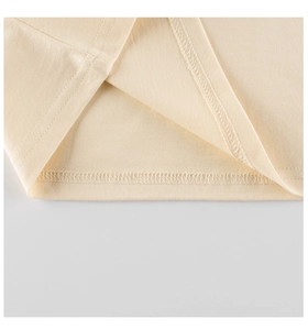 Detailed close-up of double-needle stitching on cream cotton t-shirt hem for children