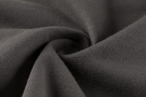 Close-up of soft charcoal grey knitted cotton fabric showing texture and drape detail