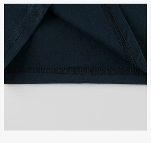Detailed close-up of double-needle hem stitching on a navy blue cotton t-shirt