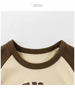 Dettaglio dello scollo rotondo raglan e cuciture sulla t-shirt marrone a contrasto bimbi