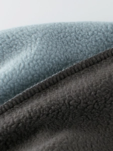 Detail of warm fleece fabric with grey and blue splicing and durable overlock stitching