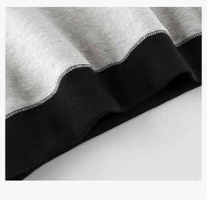 Detailed close-up of grey fleece sweatshirt hem with black ribbed elastic cuff and stitching