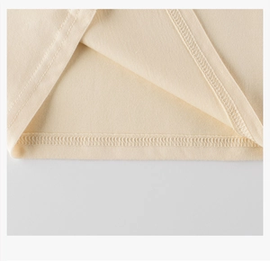 Detailed close-up of double-needle stitching on kids' cream cotton long-sleeve tee