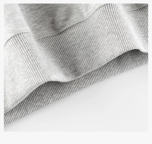 Close-up of light grey fleece hoodie showing high-density ribbed hem and fine stitching