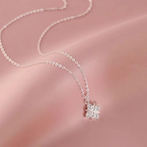 Elegant silver cross star necklace with crystal stones on a soft pink satin backdrop