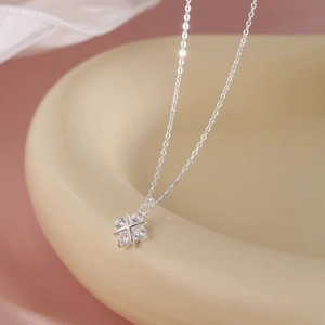 Minimalist silver cross star pendant necklace with cubic zirconia on ceramic tray