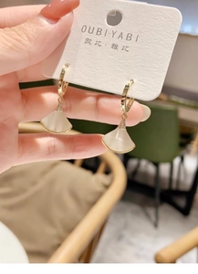 Detalle de pendientes dorados en abanico con nácar blanco e incrustaciones de strass