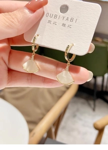 Detalle de pendientes dorados en forma de abanico con nácar blanco y pequeños circones