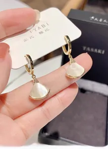 Detalle de pendientes de abanico dorados con nácar blanco y micro diamantes finos