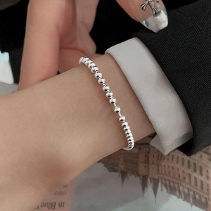Primo piano di un braccialetto di perline d'argento lucido sul polso con elegante stile di lusso